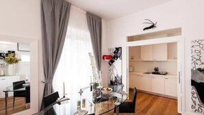 Un comedor moderno con una mesa de vidrio, sillas negras y vistas a la cocina.