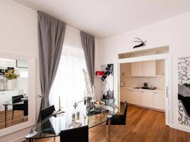Zona pranzo moderna con tavolo in vetro, sedie nere e vista sulla cucina.