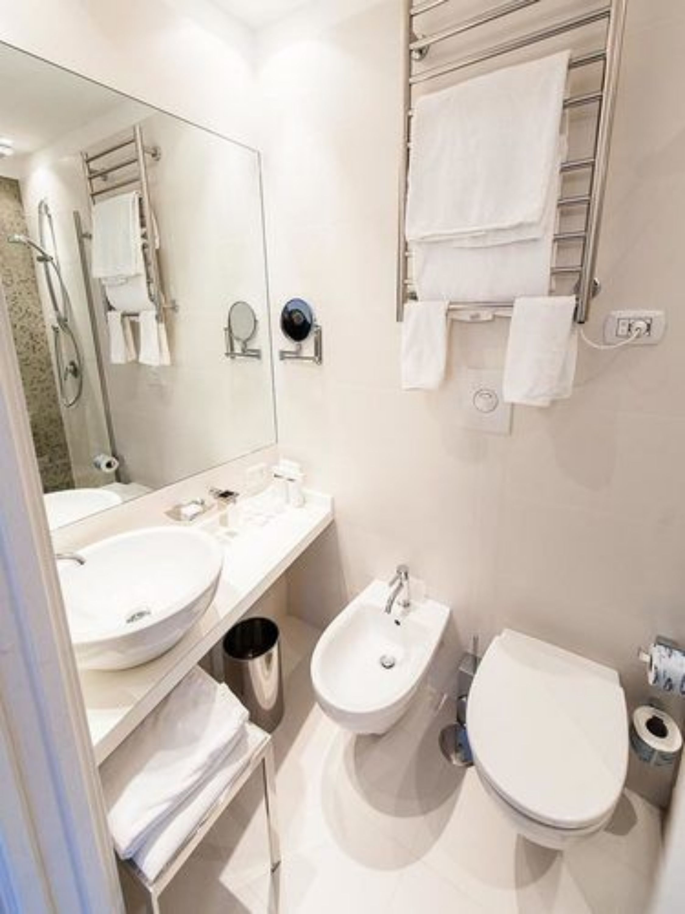 A modern bathroom with two sinks, a bidet, a toilet, and a towel rack.