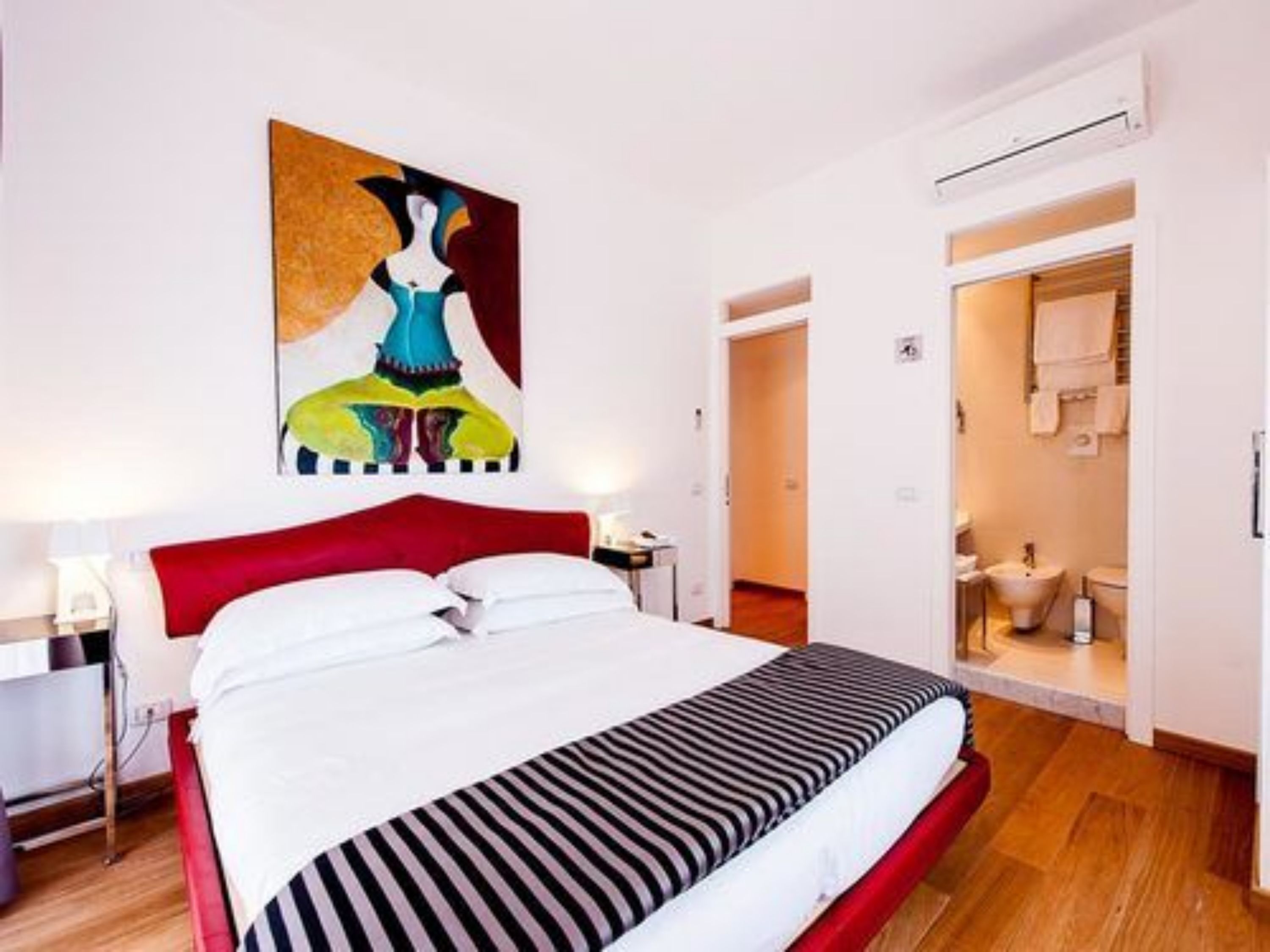 Ein Hotelzimmer mit Bett, einem Bild an der Wand und einem durchgegangenen Badezimmer.