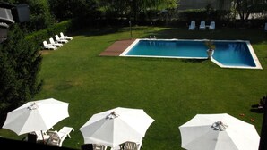 A backyard with a swimming pool, lawn chairs, and umbrellas.