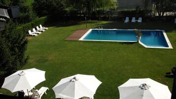 Un patio trasero con piscina, sillas de jardín y sombrillas.