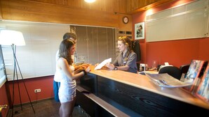 A reception desk with a wooden counter, a clock on the wall, and a window with blinds.