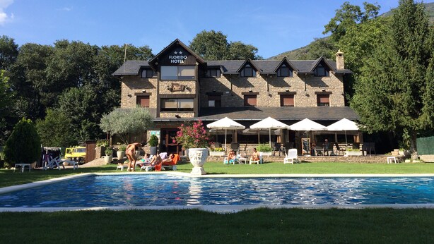 A hotel with a swimming pool, outdoor seating, and a mountain backdrop. - Florido Hotel (Sort)