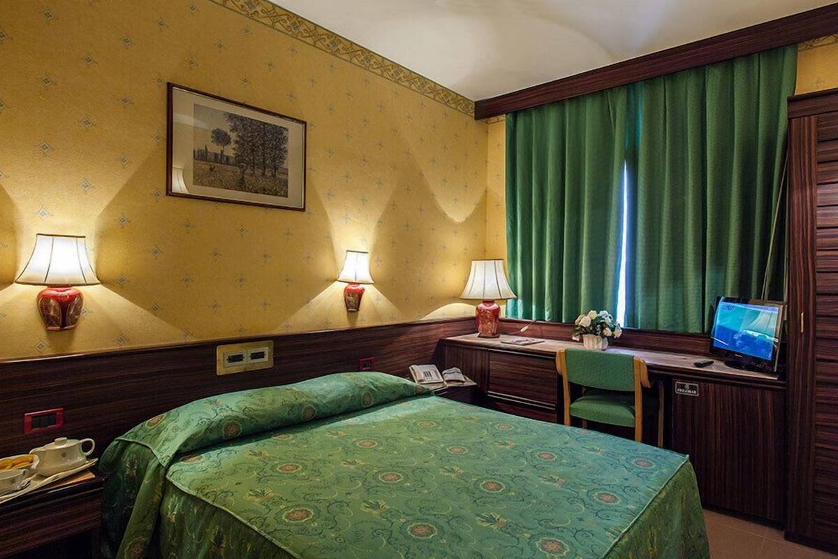 Ein Hotelzimmer mit Bett, Schreibtisch und Fernseher.