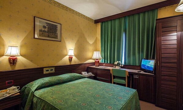 Una habitación de hotel con cama, escritorio y televisor.