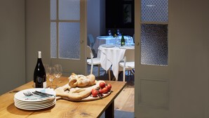A dining table set with plates, cutlery, a bottle of wine, bread, and tomatoes. - Mas Vivent (Vilamaniscle)