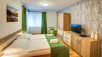 Habitación de hotel con cama, televisor, armario y escritorio.