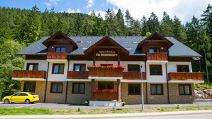 A multi-story hotel with a stone facade, wooden balconies, and a sign reading "Apartman TRI STUDNICKY". - Apartmány TRI STUDNIČKY (Demanovska Dolina)