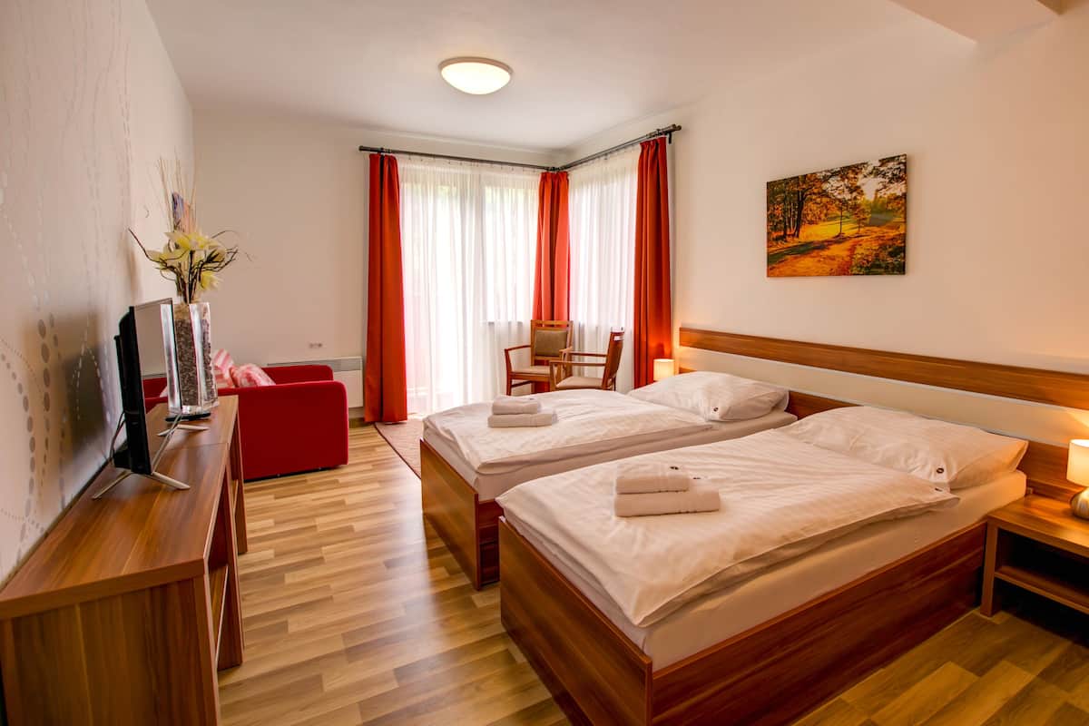 Ein Hotelzimmer mit zwei Betten, einem Schreibtisch mit Computer, einem Sessel und einem Bild an der Wand.
