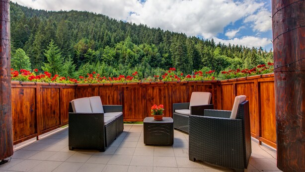 An outdoor patio with wicker furniture and a wooden fence. - Apartmány TRI STUDNIČKY (Demanovska Dolina)