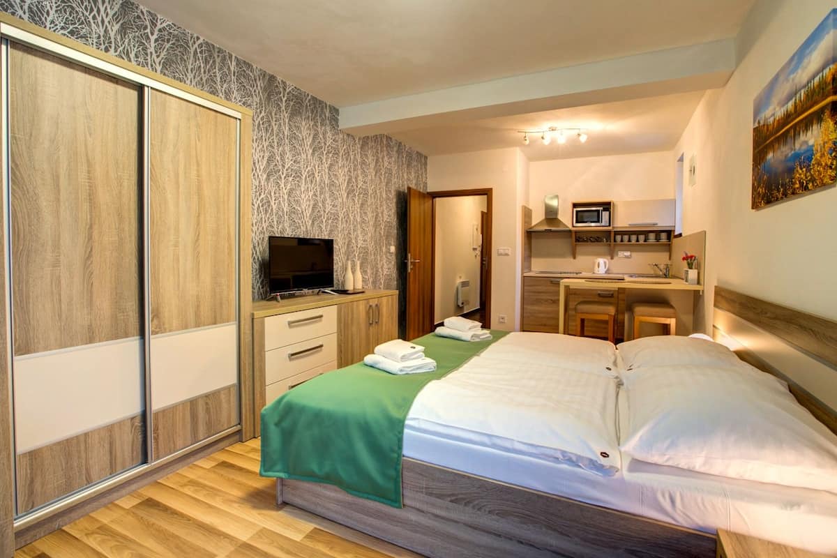 Ein Hotelzimmer mit Bett, Schreibtisch, Fernseher und Kleiderschrank.