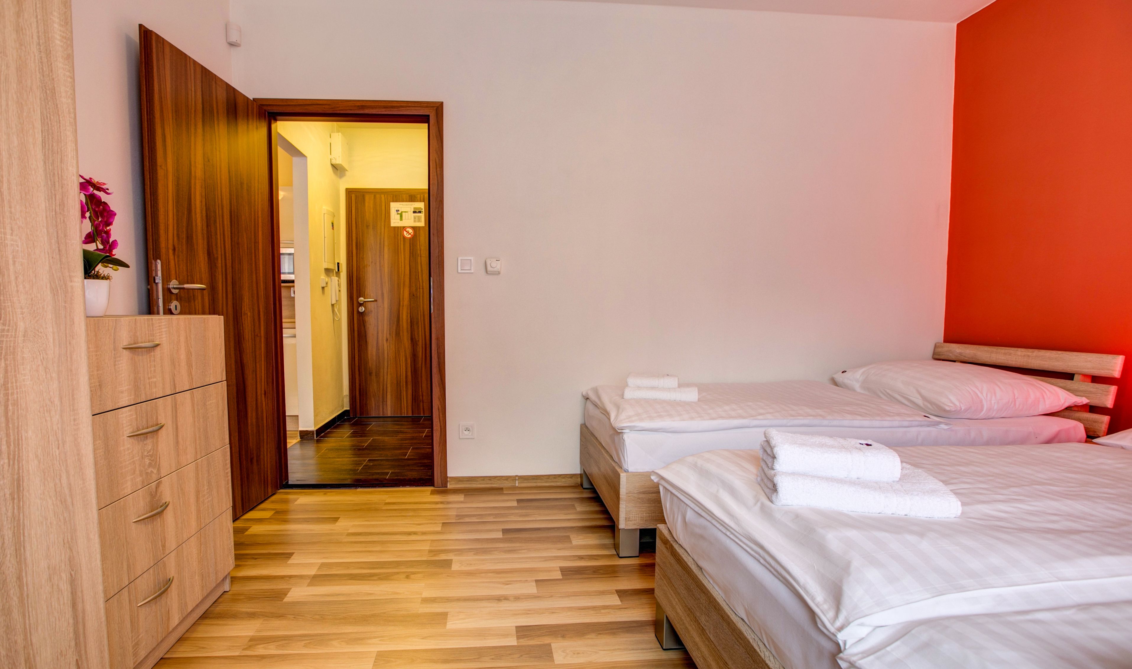 Ein Schlafzimmer mit zwei Betten, einem Holzschrank und einem durchgehenden Türspalt einsehbarer Badezimmers.