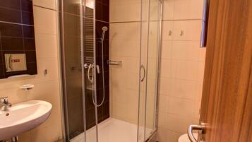 Un baño moderno con ducha de vidrio, lavamanos e inodoro.