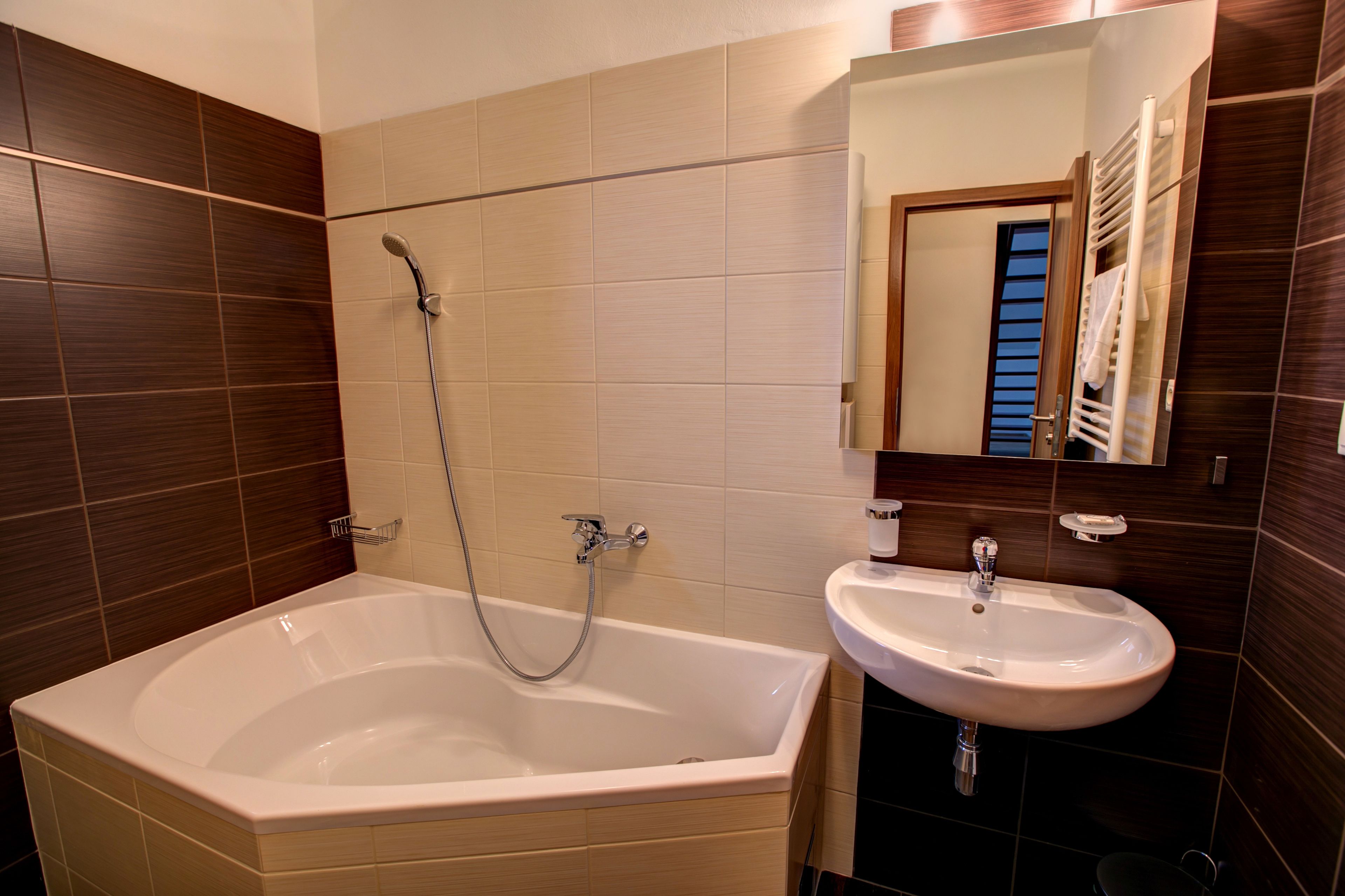 Un baño moderno con una bañera independiente, un lavamanos y un espejo sobre el lavamanos.