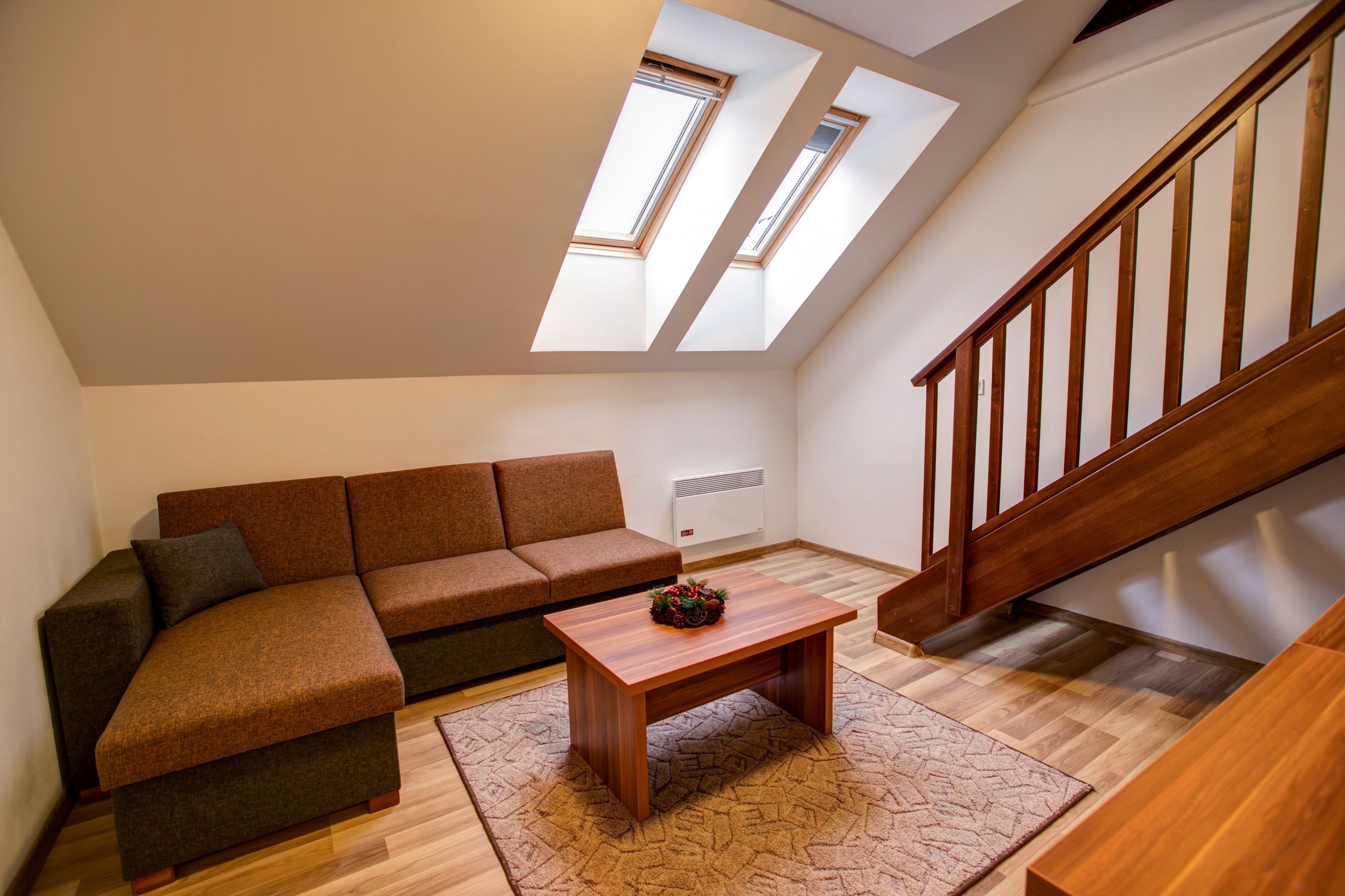 A modern living room with a sectional sofa, a wooden coffee table, and a staircase.