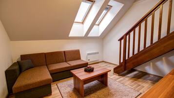 A modern living room with a sectional sofa, a wooden coffee table, and a staircase.
