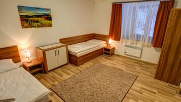 A bedroom with a bed, bedside tables, a nightstand, a rug, a painting, and a window with curtains.