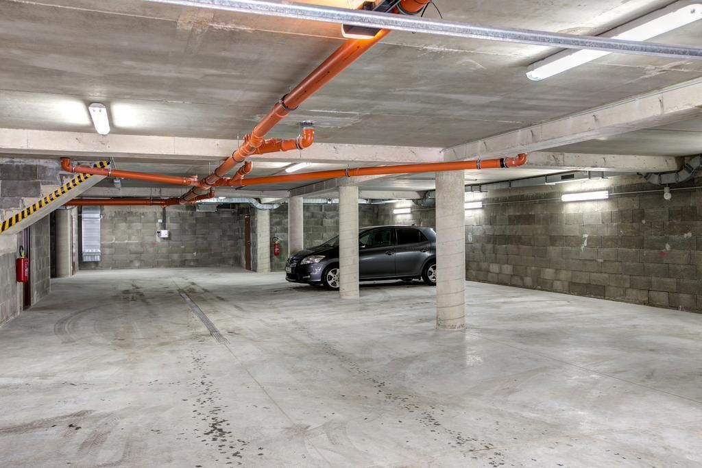 A multi-level parking garage with concrete pillars and orange pipes.