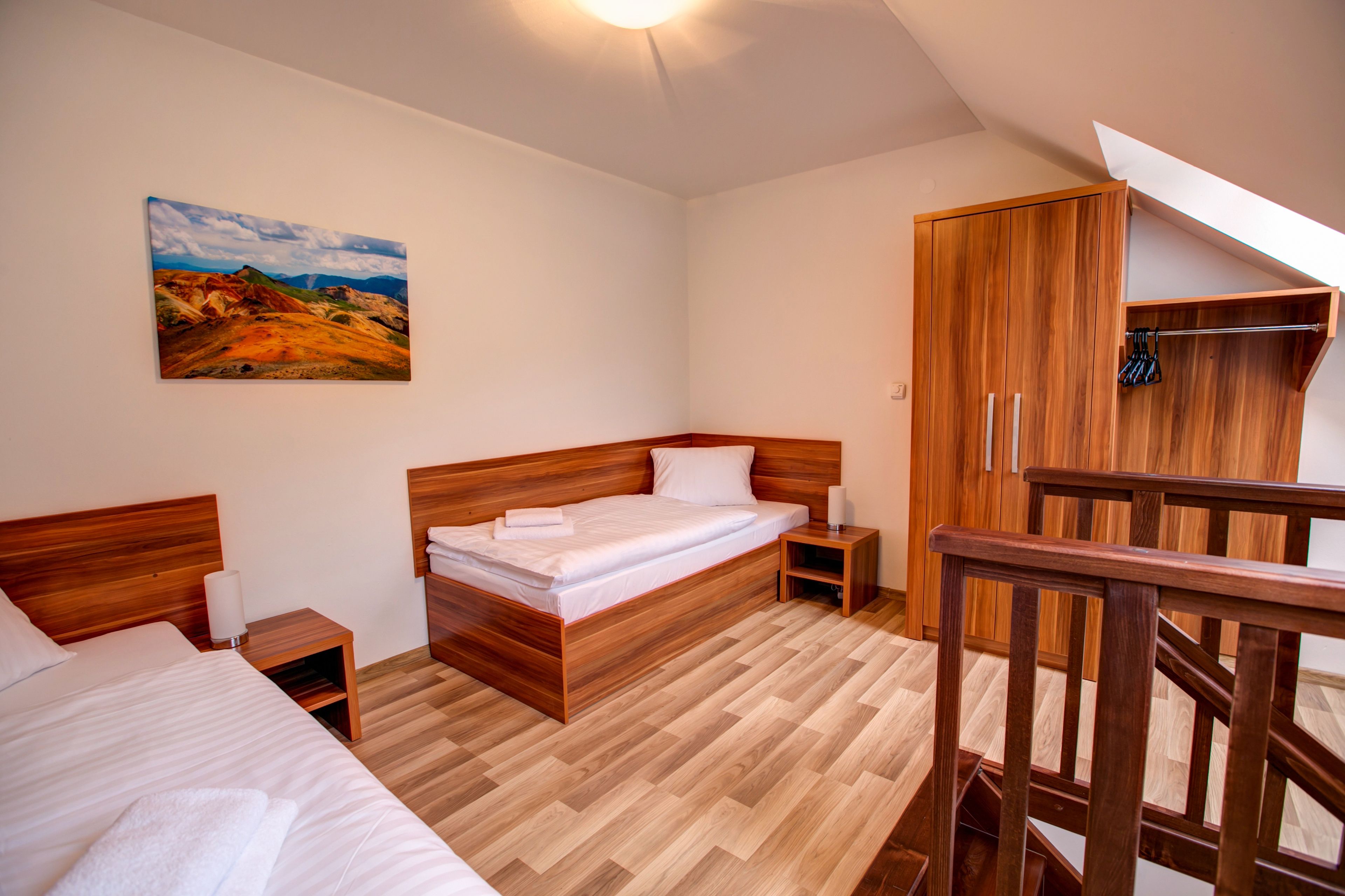 Um quarto com cama de madeira, guarda-roupa de madeira e um quadro na parede.