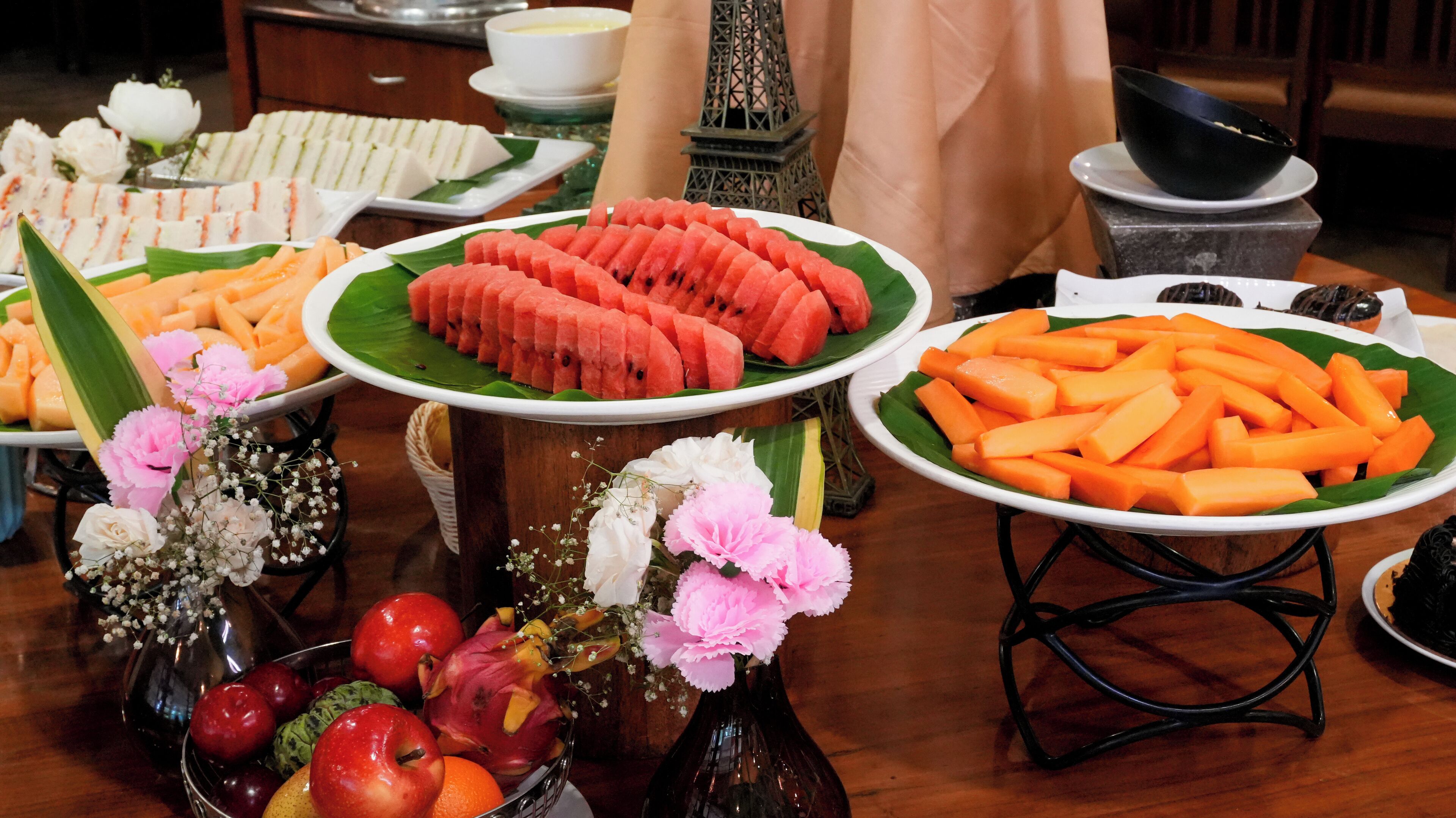 A buffet table with various food items and a decorative Eiffel Tower model.
