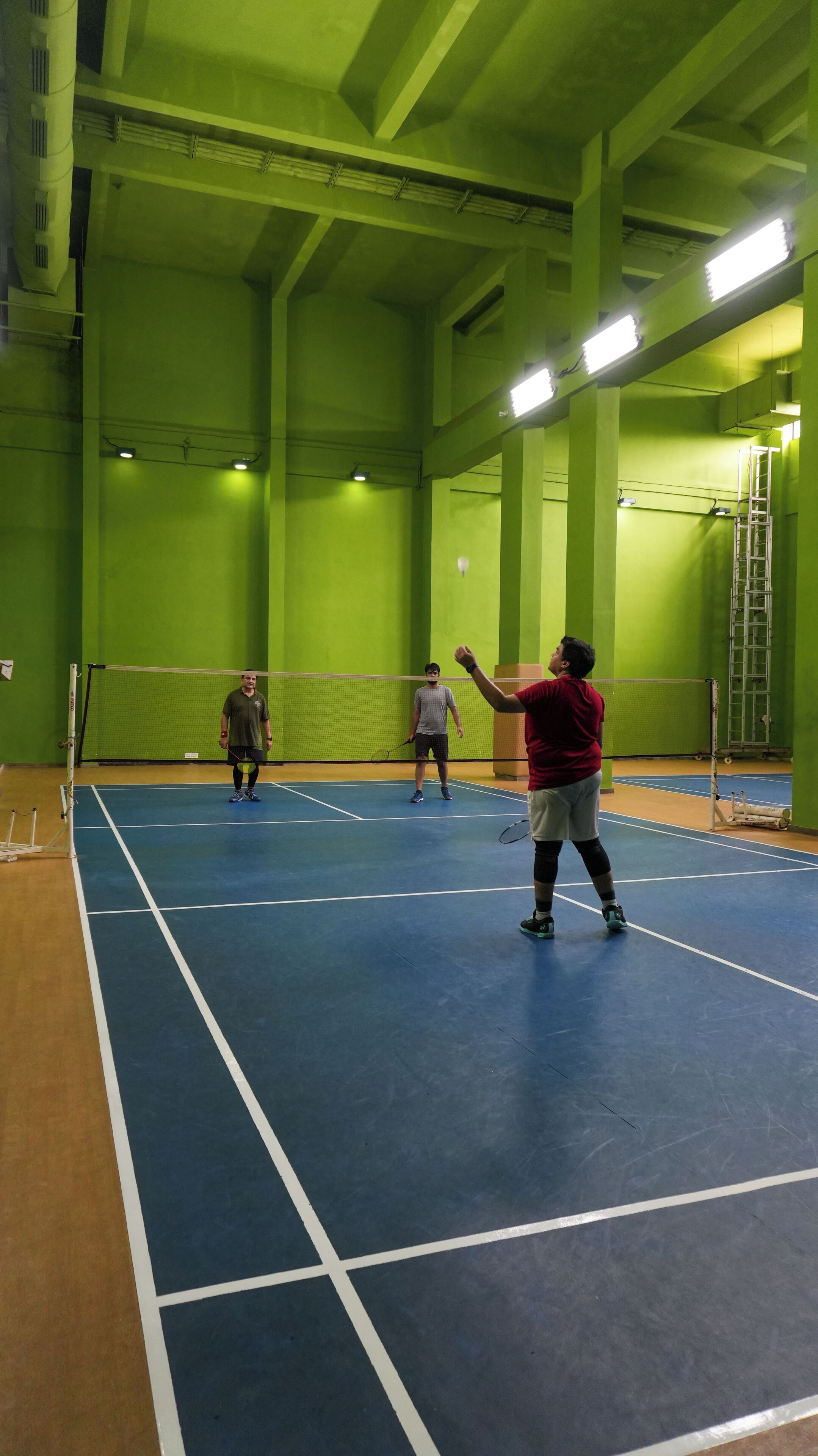 Una palestra per badminton con pareti verdi e pavimento blu.