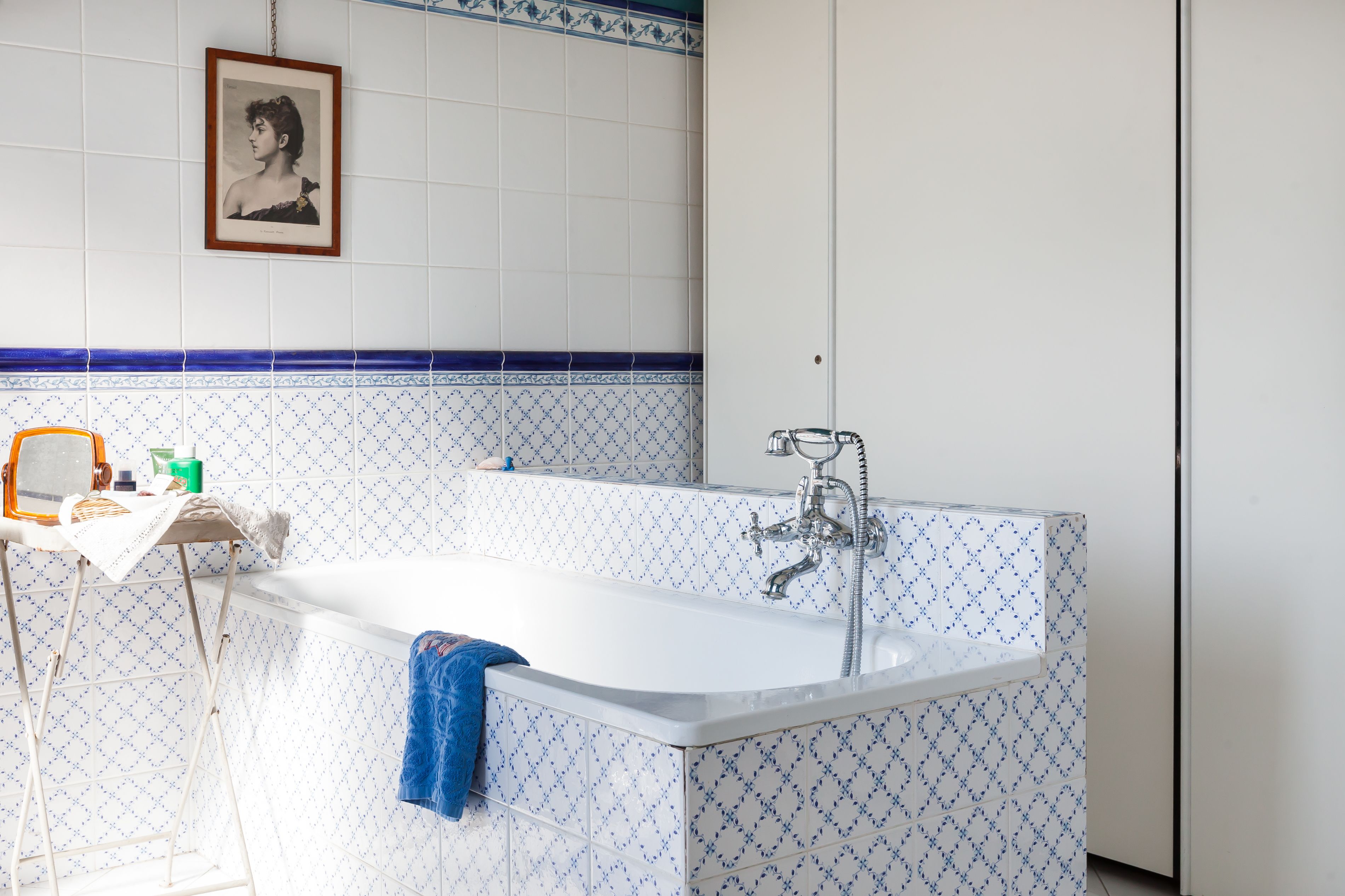 A bathroom with a white bathtub, a towel hanging on the side, and a framed picture on the wall.