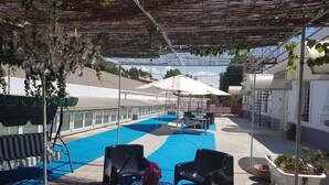 Ein Poolbereich auf dem Dach mit blauem Pool, Außenmöbeln und einer Pergola.