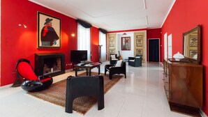 Ein Zimmer mit roter Wand, Kamin, Fernseher, Sofa und Schrank.