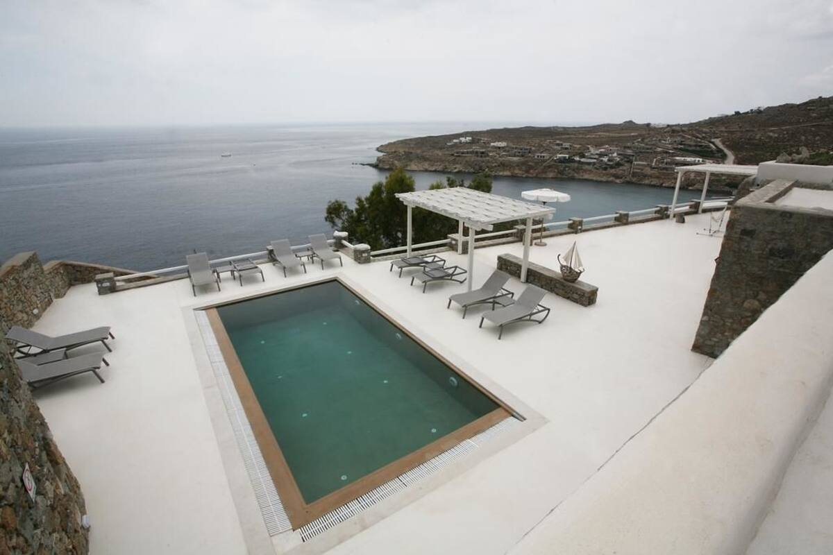 A rooftop pool with lounge chairs and a view of the sea.