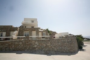 Un edificio de paredes de piedra con varios balcones y fachada blanca.