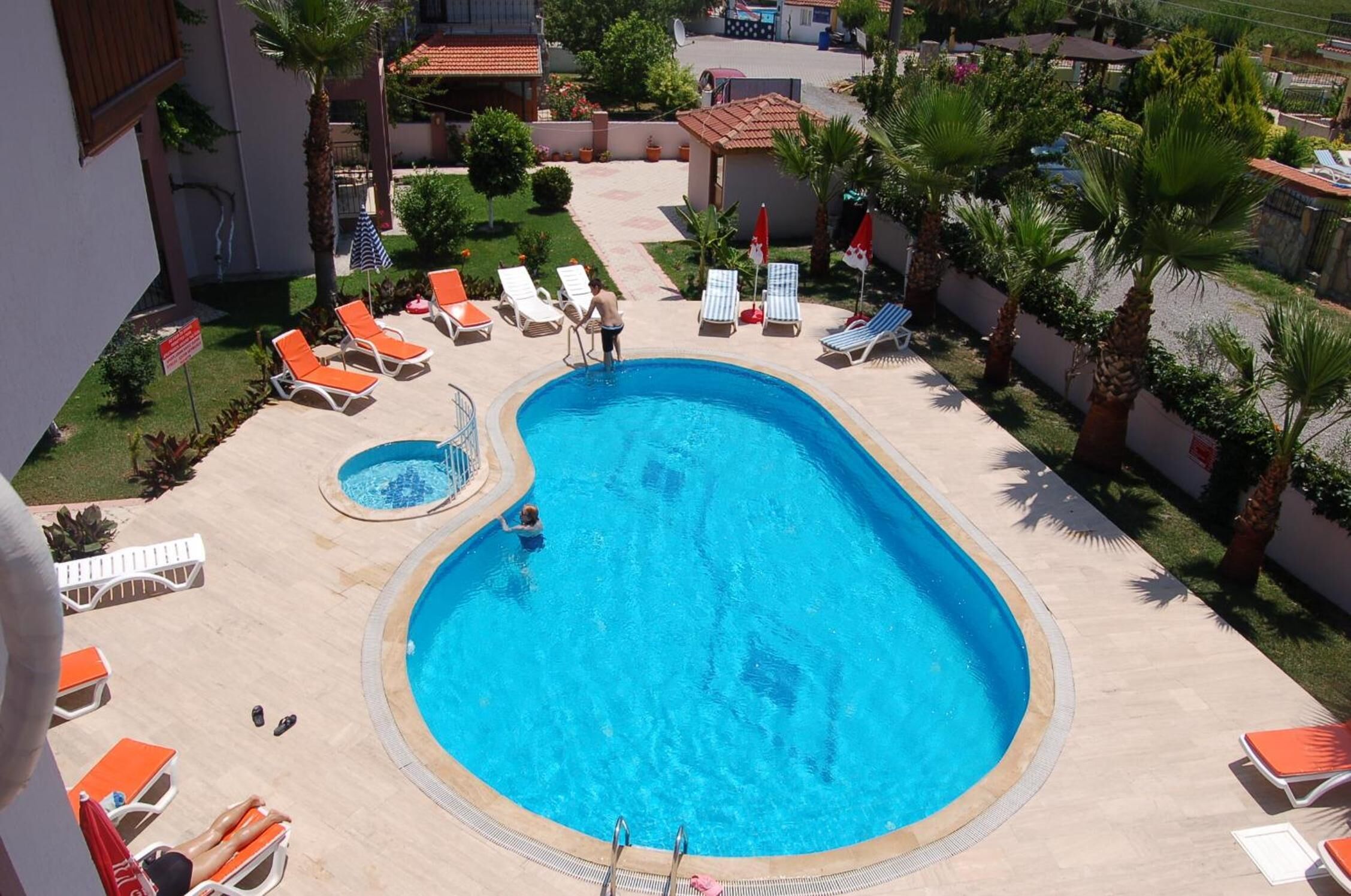 A swimming pool surrounded by lounge chairs and palm trees.