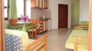 Cuina compacta amb armaris de fusta, una taula de dinar amb caires i una petita zona d'esbarjo.
