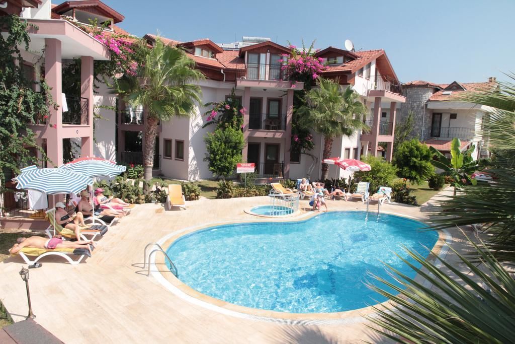 Une piscine entourée de chaises longues et de parasols, avec un bâtiment en arrière-plan.