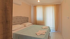 Un dormitori amb un llit, una tauleta de nit i una finestra amb cortines.
