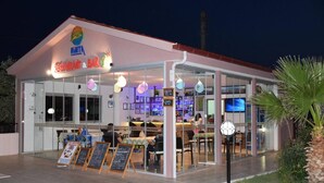 Un restaurant amb façana de vidre, terrassa a l'aire lliure i un cartell que anuncia cerveses i crispetes.