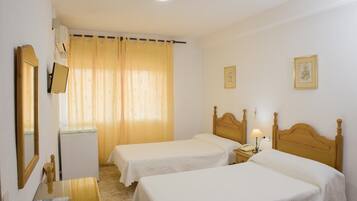 Habitació d'hotel amb dos llits individuals, un escriptori amb cadira, un telèfon i un mirall.