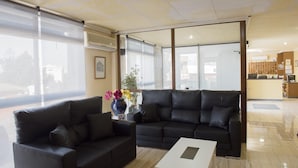 En moderne stue med en sort lædersofa, et sofabord og en vase med blomster.