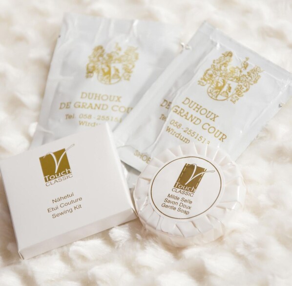 A white box labeled "Touch CLASSIC" with a logo, and three white sachets with gold text and a logo, all on a white fluffy surface. - Hotel Duhoux Leeuwarden (Wirdum)
