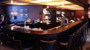 A bar area with a long counter, multiple stools, and a patterned wall. - Hotel Duhoux Leeuwarden (Wirdum)