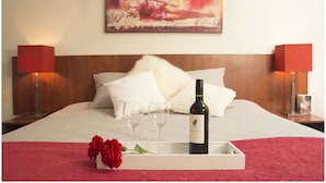 A neatly made bed with white linens, two bedside lamps, a bottle of wine, two empty wine glasses, and a tray with a red rose. - Hotel Duhoux Leeuwarden (Wirdum)