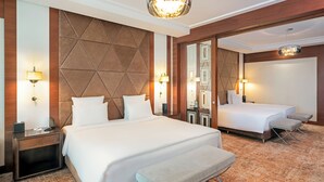 Une chambre d’hôtel avec un grand lit, un lit plus petit, un banc et un miroir.