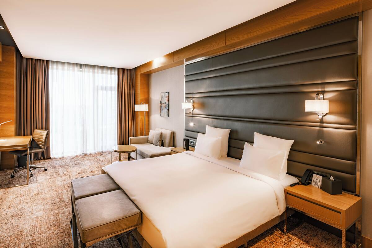 Ein Hotelzimmer mit einem großen Bett, einem Schreibtisch, einem Stuhl und einem kleinen Tisch.