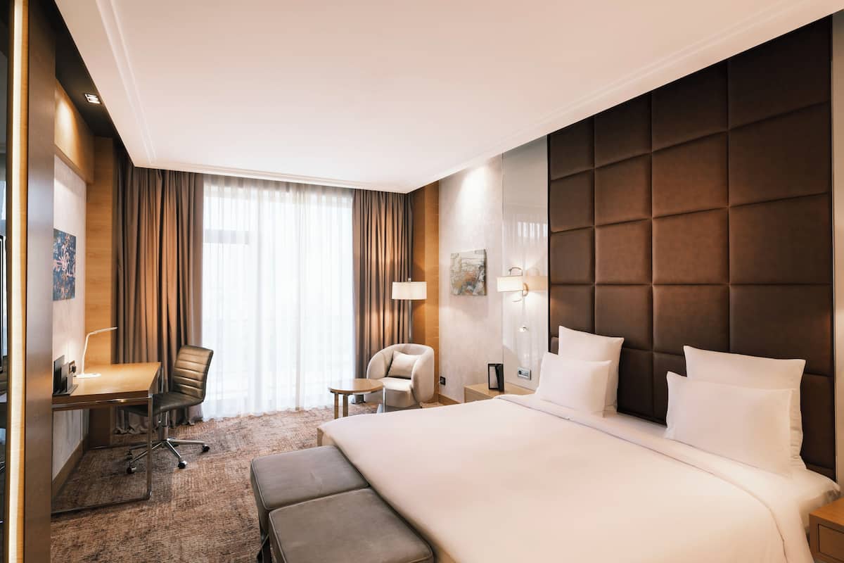 Ein Hotelzimmer mit einem großen Bett, einem Schreibtisch mit Stuhl, einem kleinen Tisch und einer Couch.