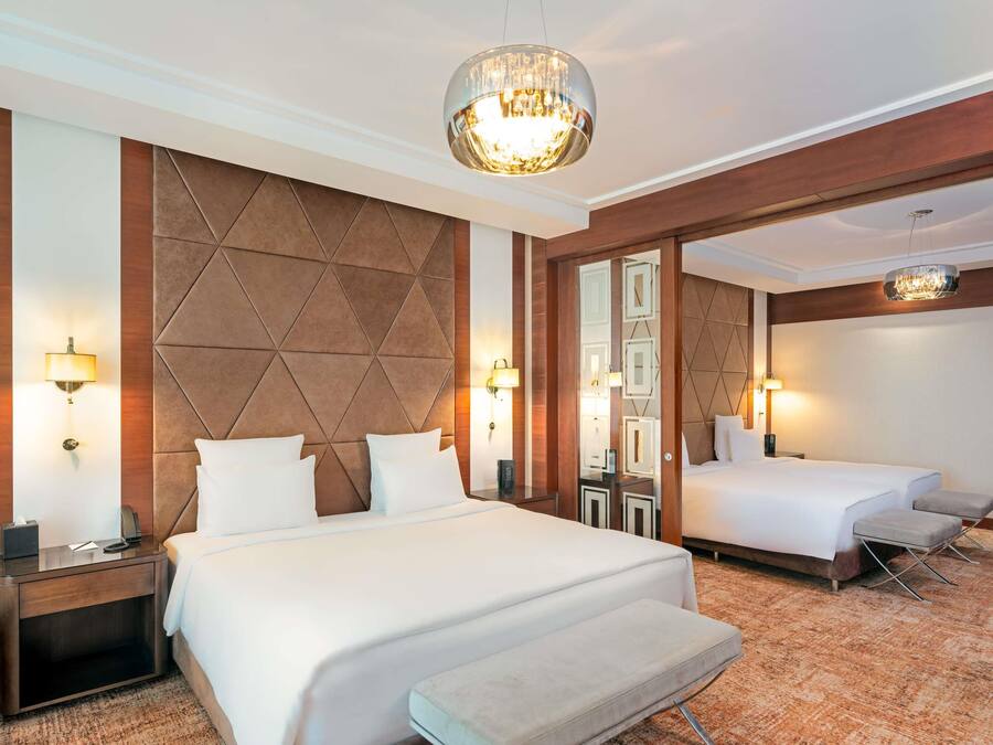 A hotel room with a large bed, a smaller bed, a nightstand, a lamp, and a mirror.