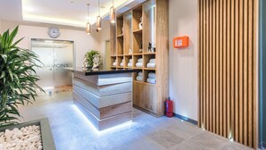 Un espace d’accueil moderne avec un comptoir de réception en bois, une horloge et un extincteur.