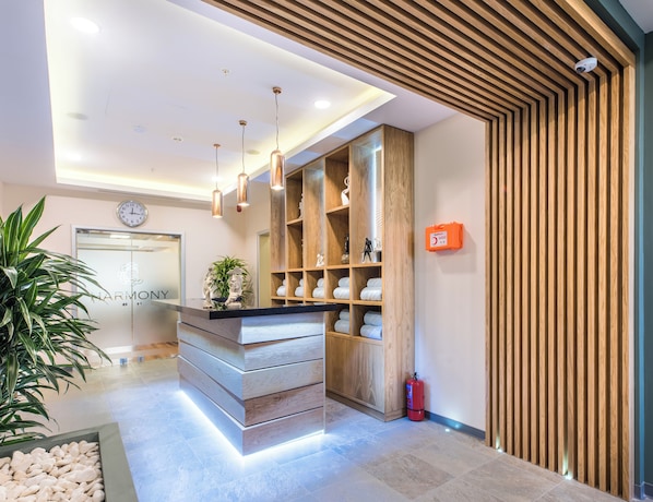 Un espace d’accueil moderne avec un comptoir de réception en bois, une horloge et un extincteur.