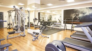Une salle de sport équipée de tapis de course, d’appareils de musculation et d’haltères.