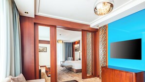 Une chambre d’hôtel avec un canapé, une table basse en bois, une télévision et un lit.