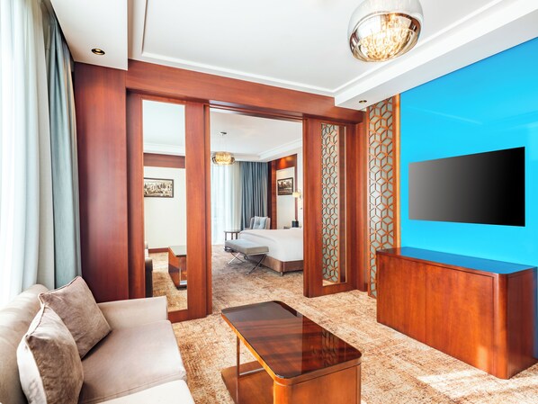 A hotel room with a sofa, a wooden coffee table, a TV, and a bed.